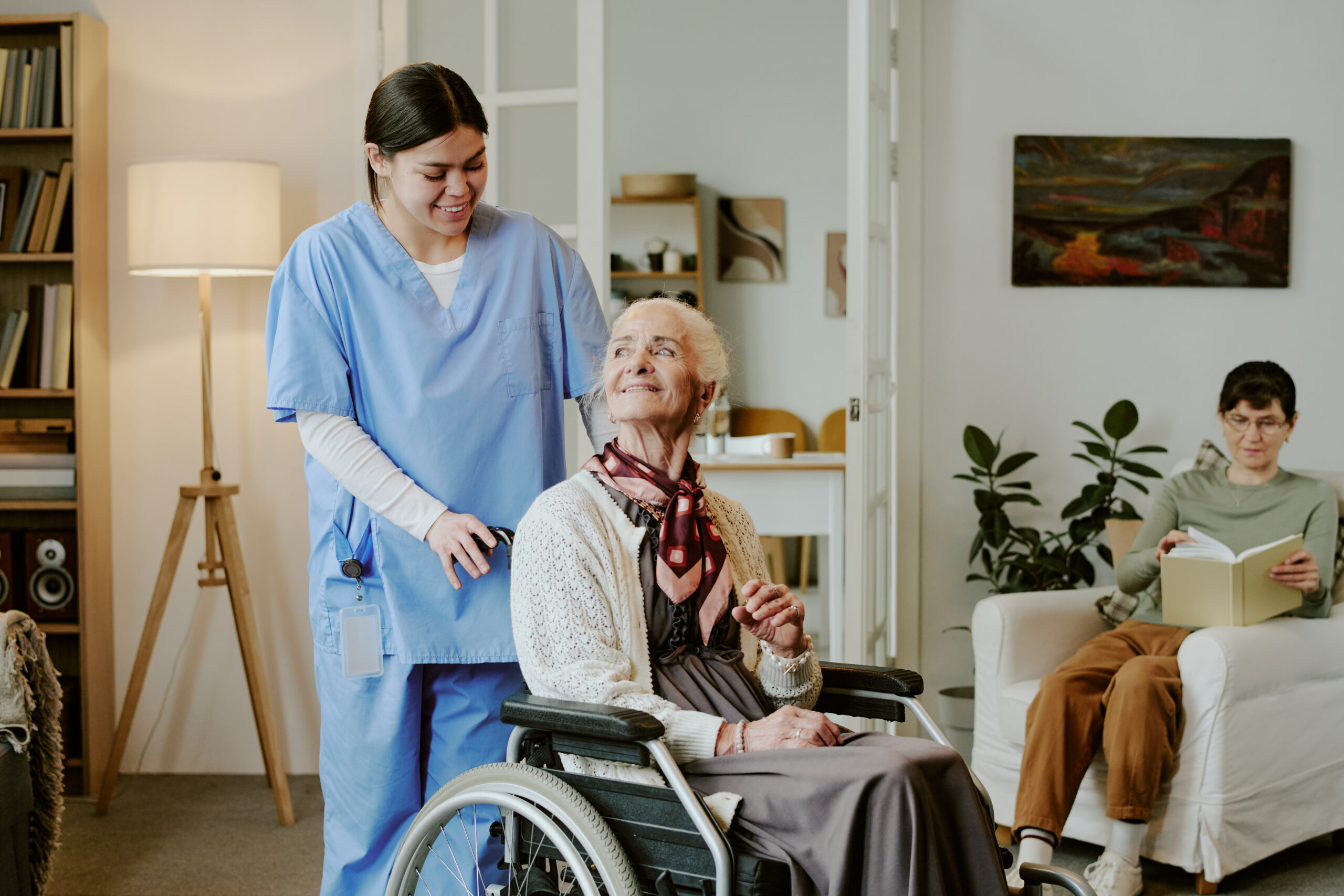 middle aged hispanic female nurse assisting senior woman in wheelchair